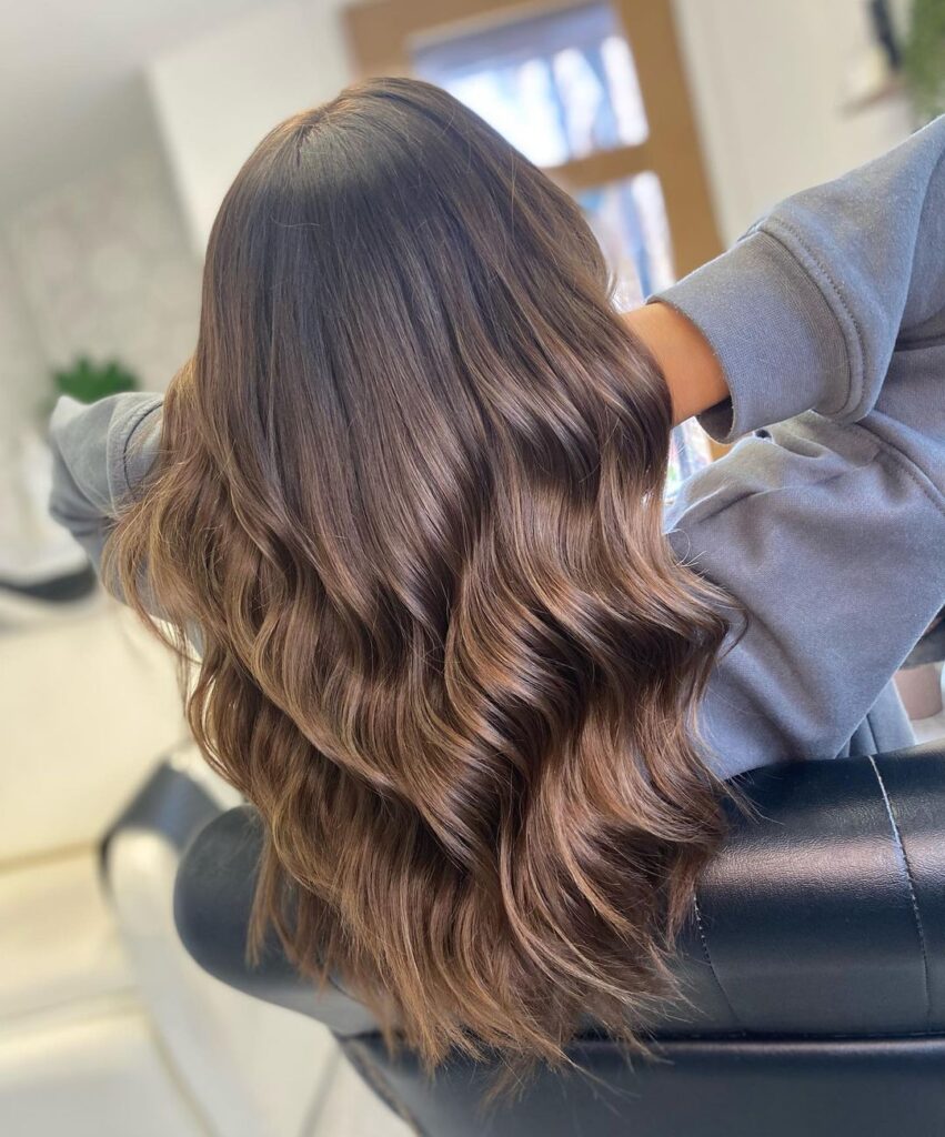 Glossy brunette hair styled into flowing waves